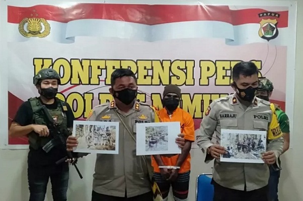 Tersangka MT, anak buah KKB Guspi Waker, dengan tangan diborgol dan diapit oleh aparat bersenjata lengkap dihadirkan saat konferensi pers Polres Mimika,